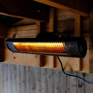 A black rectangular wall mounted electric patio heater glowing orange