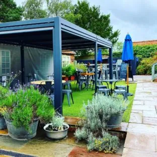 A rectangular grey metal gazebo covering 4 tables in a pub garden