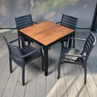 A budget range outdoor dining table and chairs set. Dark grey frames with a laminate wood effect table top. Chairs set round the table on a grey outdoor deck