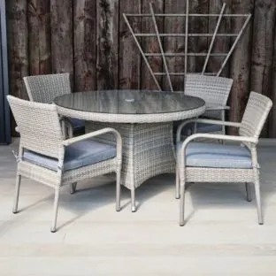 A synthetic grey rattan outdoor round dining table and 4 matching armchairs on a grey outdoor deck