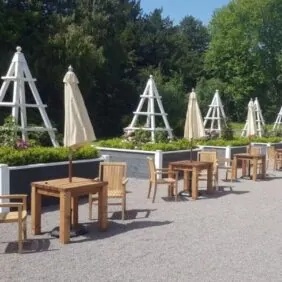 teak chairs and wooden tables, alongside bespoke grey planters